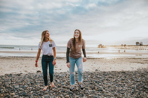 Friends laughing and walking on the beach while wearing noz eco friendly sunscreen on their nose